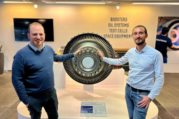 A picture of Benoît Dompierre and Gilles Ayoub, next to a piece of engine