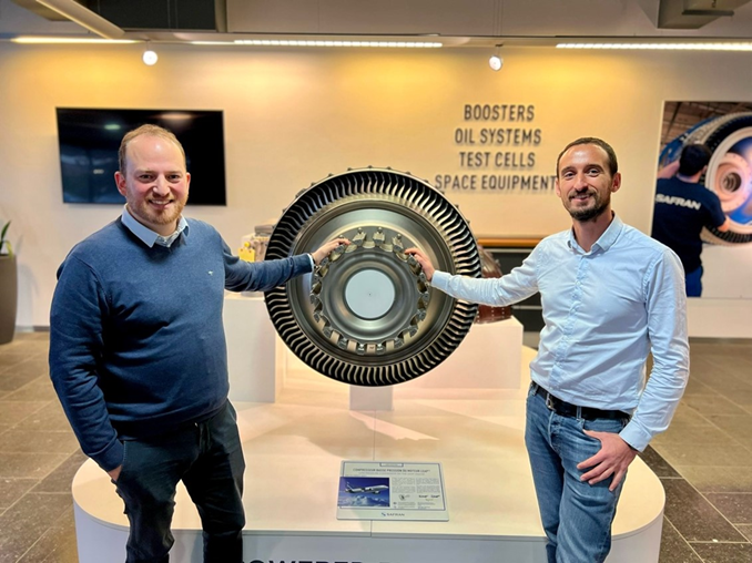 A picture of Benoît Dompierre and Gilles Ayoub, next to a piece of engine